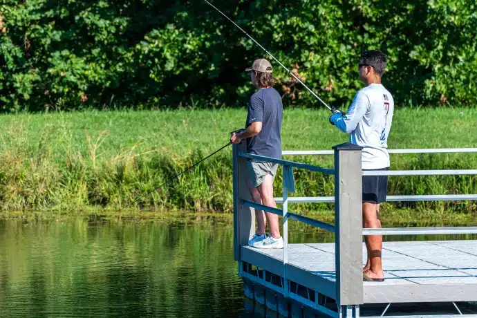 two men fishing off the dock at the community lake